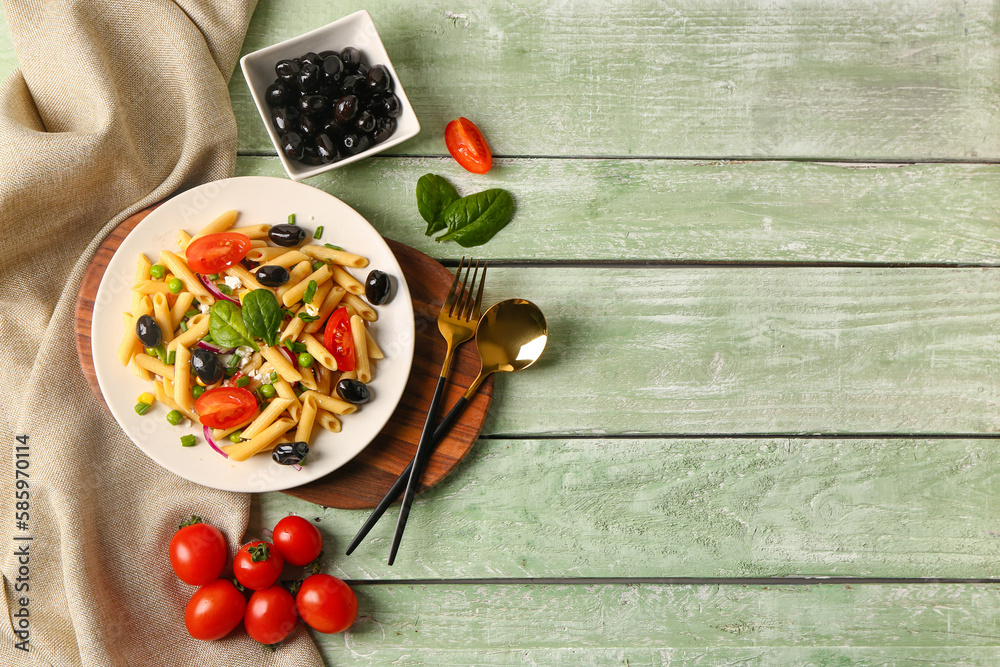 Plate with tasty pasta salad and ingredients on green wooden background