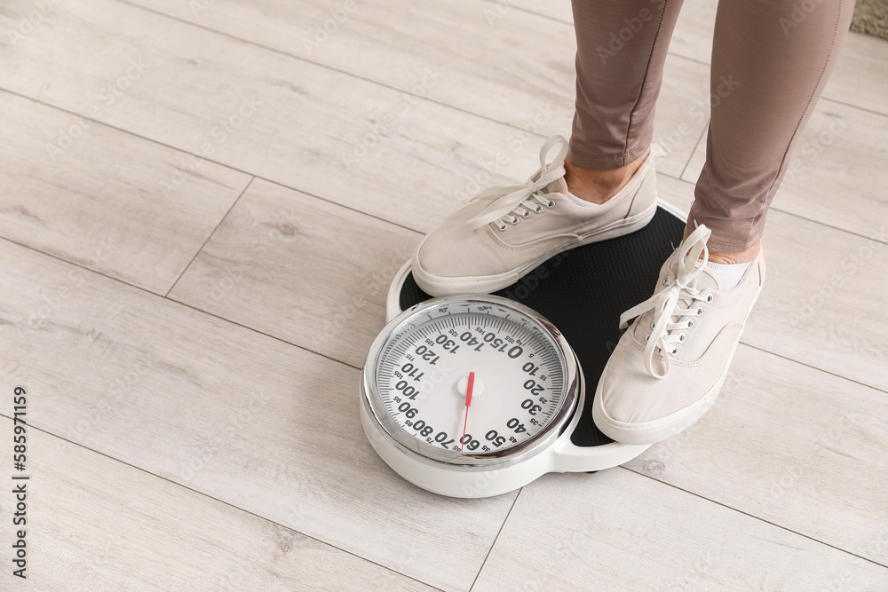 Sporty mature woman measuring her weight on scales at home, closeup