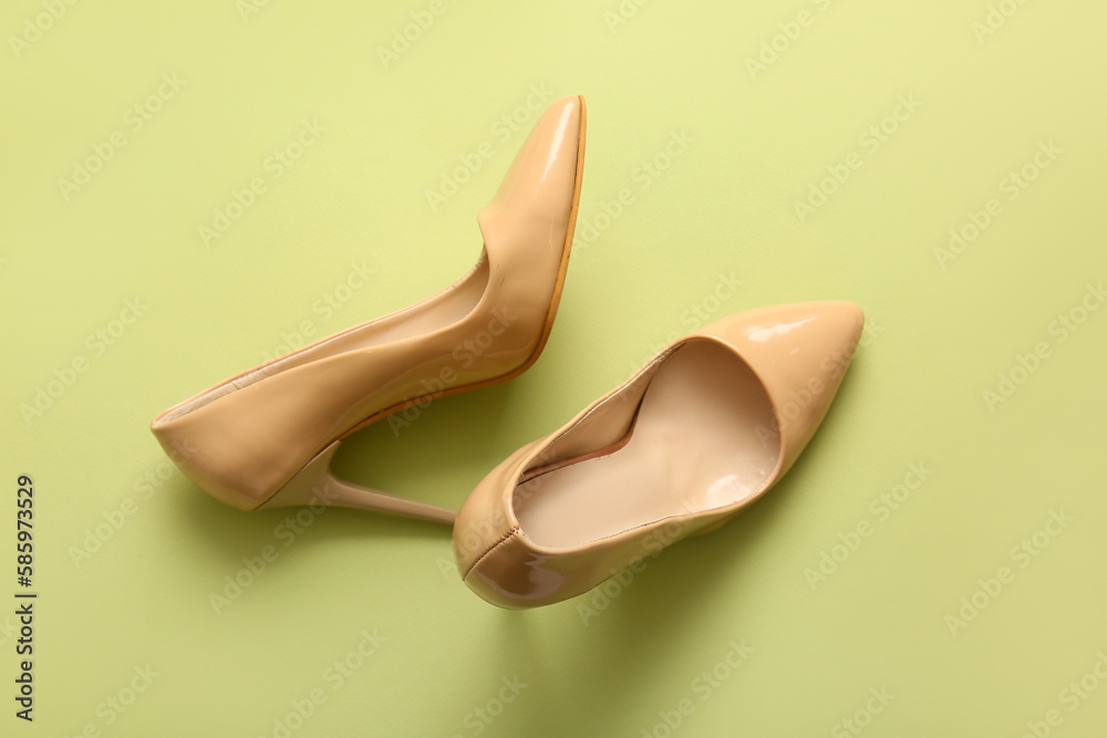 Stylish high heeled shoes on green background