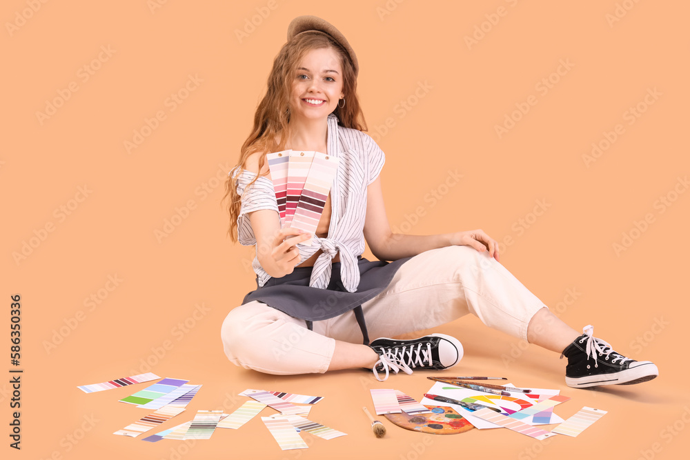 Female artist with paint color palettes sitting on beige background