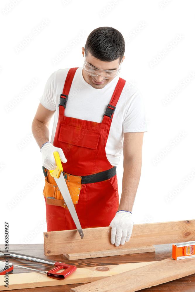 Young carpenter sawing wooden plank at table on white background