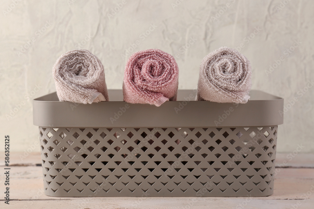 Basket with rolled soft towels on wooden table