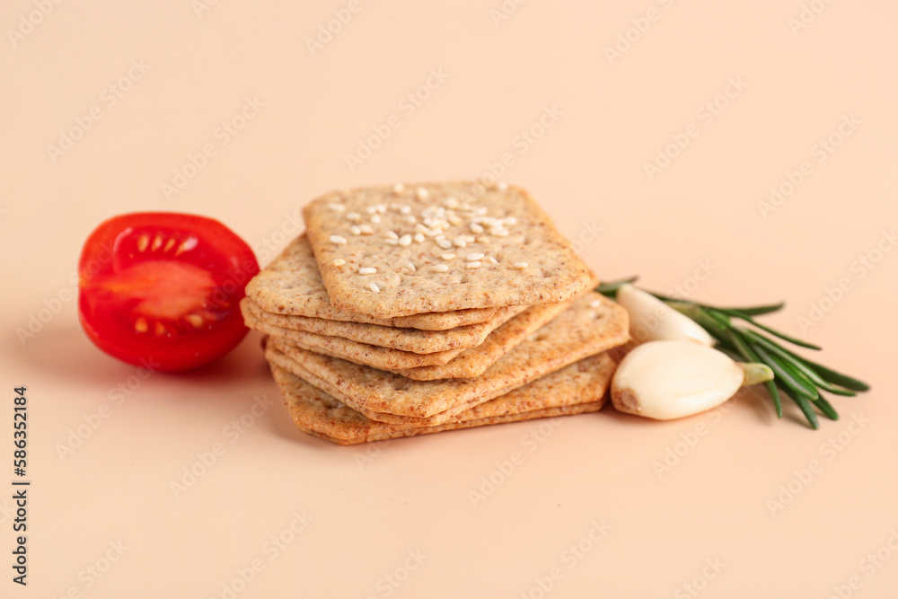 Stack of tasty crackers with sesame, garlic, tomato and rosemary on beige background