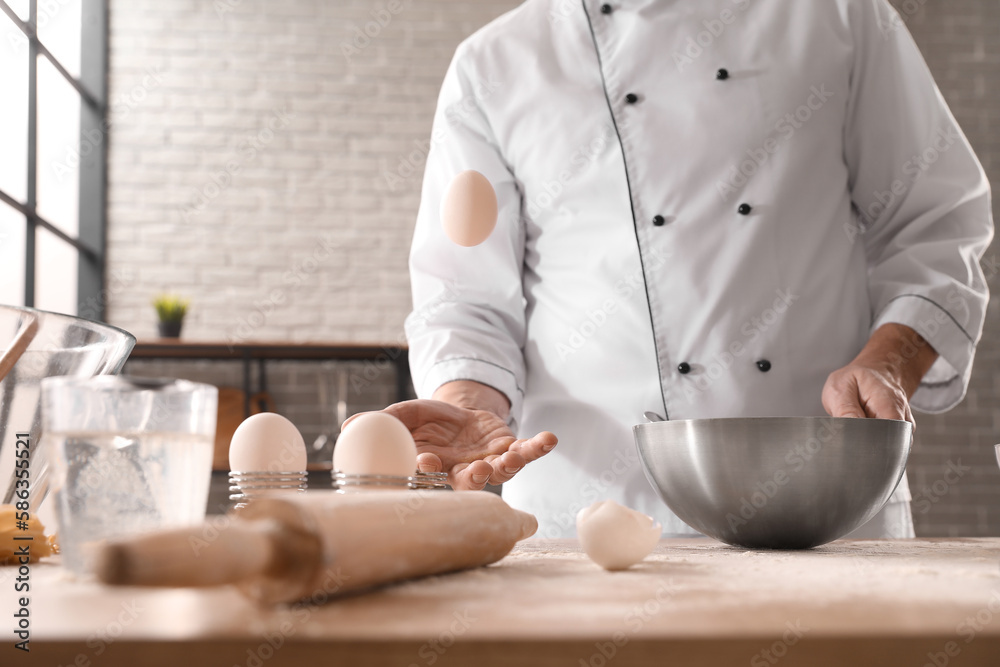 Male chef making dough for pasta at table in kitchen, closeup