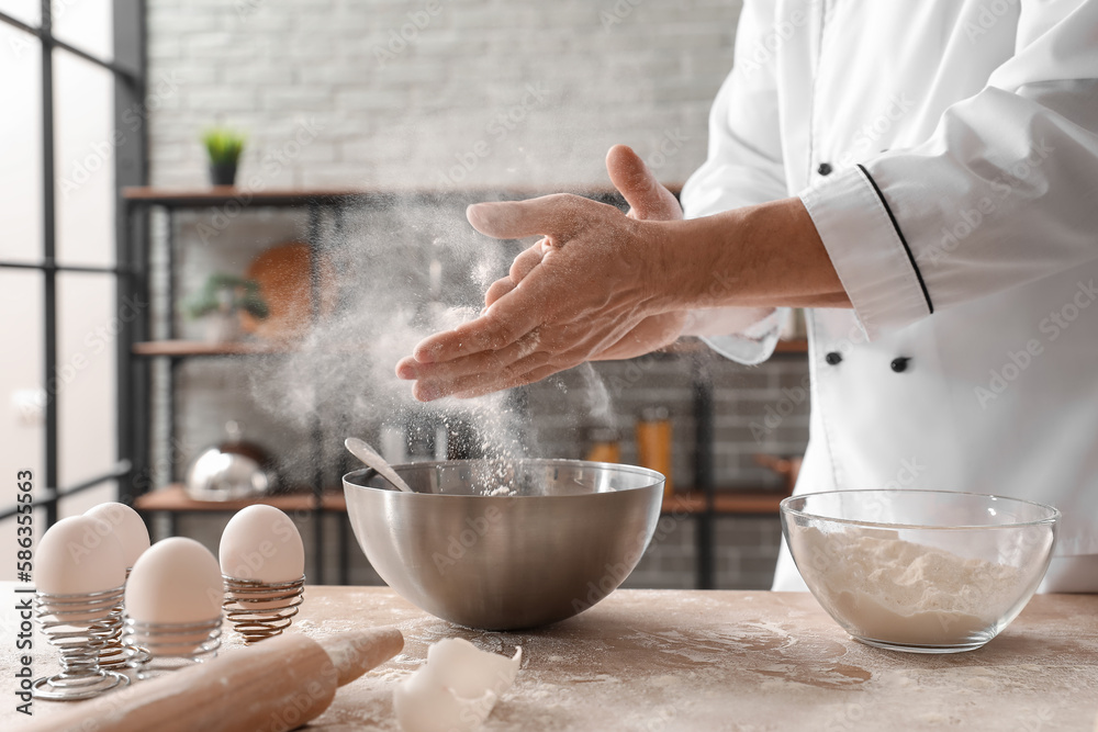 Male chef making dough for pasta at table in kitchen, closeup