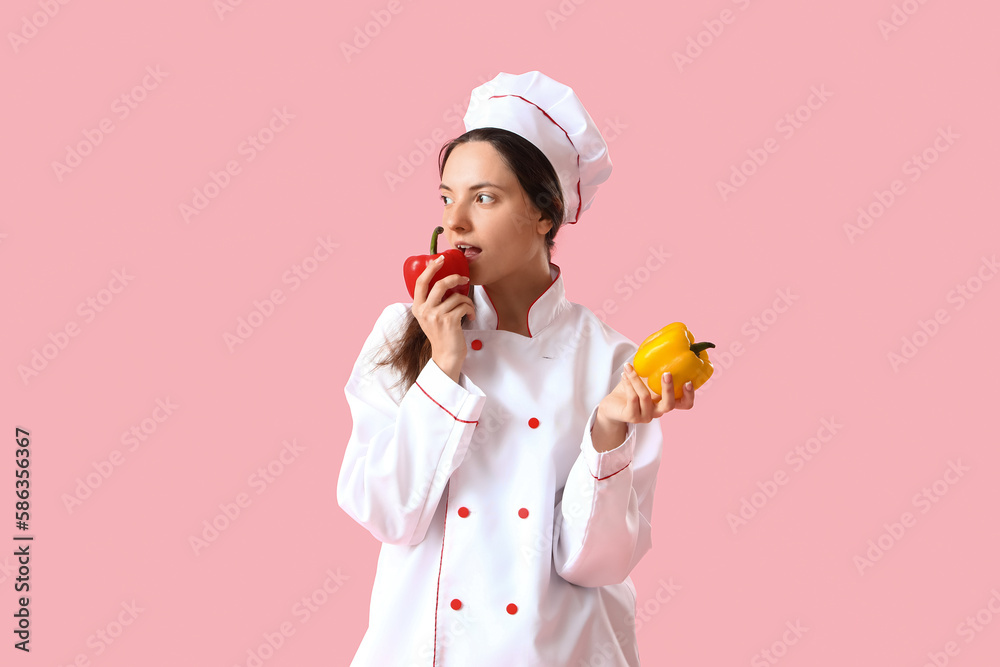 Female chef with tasty bell peppers on pink background