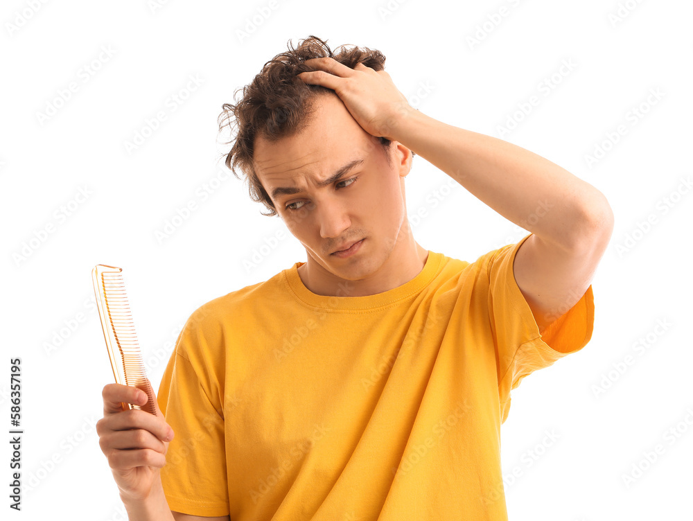 Upset young man with hair loss problem and comb on white background