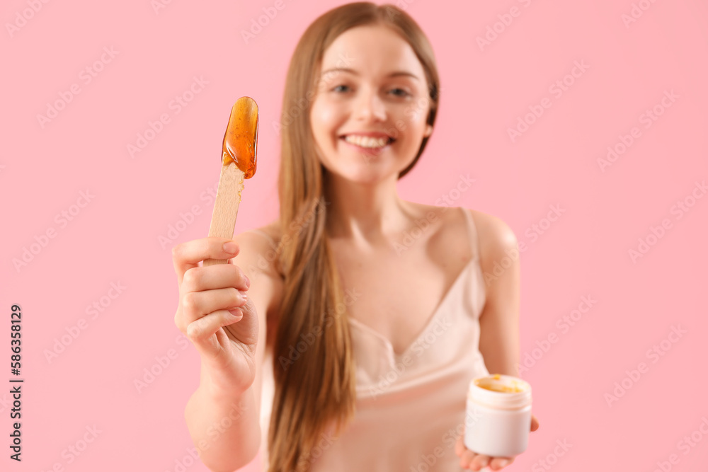 Pretty young woman with sugaring paste on pink background