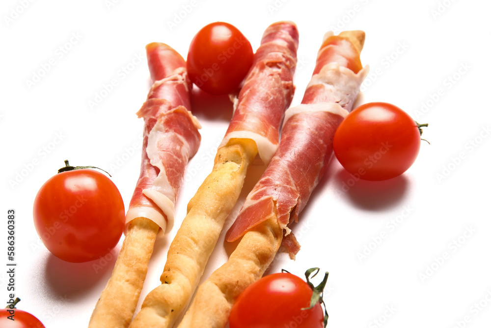 Tasty Italian Grissini with bacon and tomatoes on white background