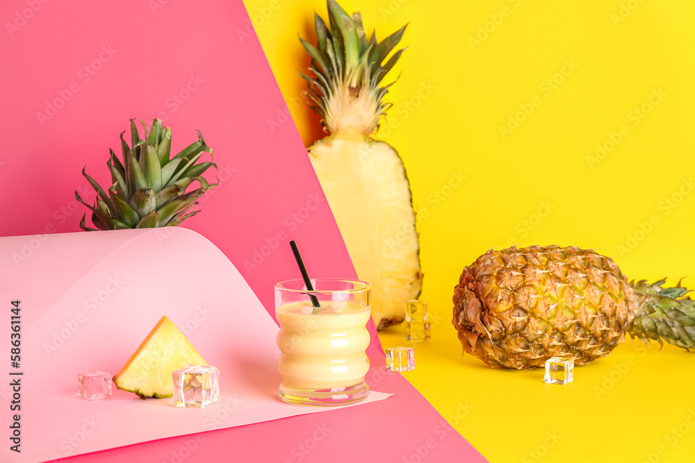 Glass of tasty pineapple smoothie, straw and ice cubes on colorful background