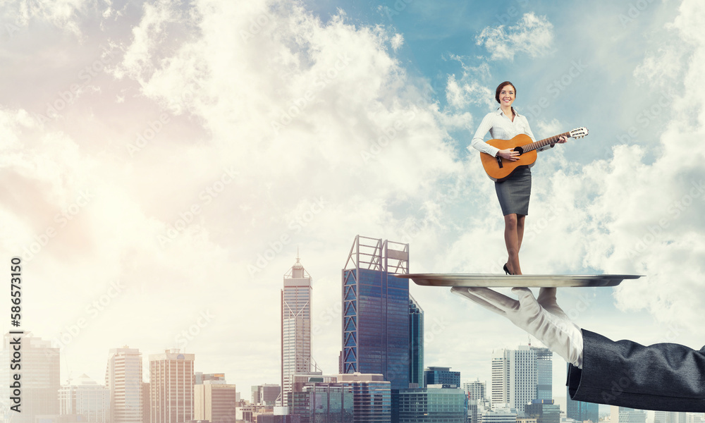 Attractive businesswoman on metal tray playing acoustic guitar against cityscape background