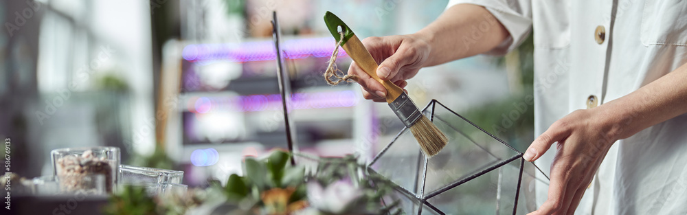 caucasian confident happy florist is working with composition made from glass stones and plants in b