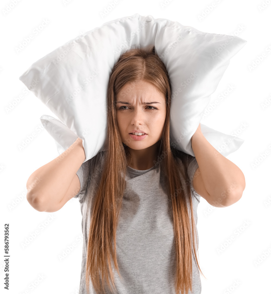 Irritated young woman with pillow suffering from loud noise on white background