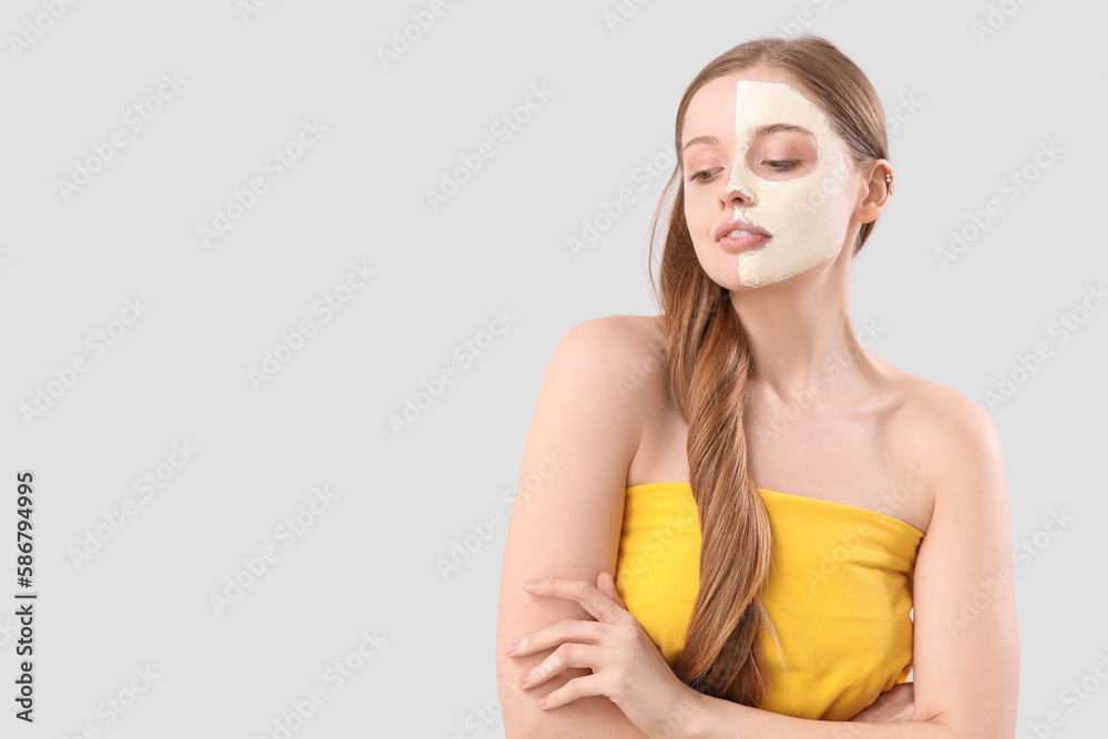 Young woman with applied turmeric mask on grey background