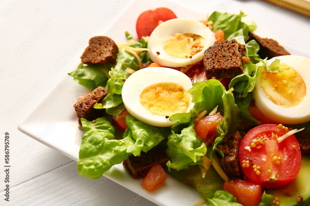 Plate of delicious salad with boiled eggs and salmon on white wooden background