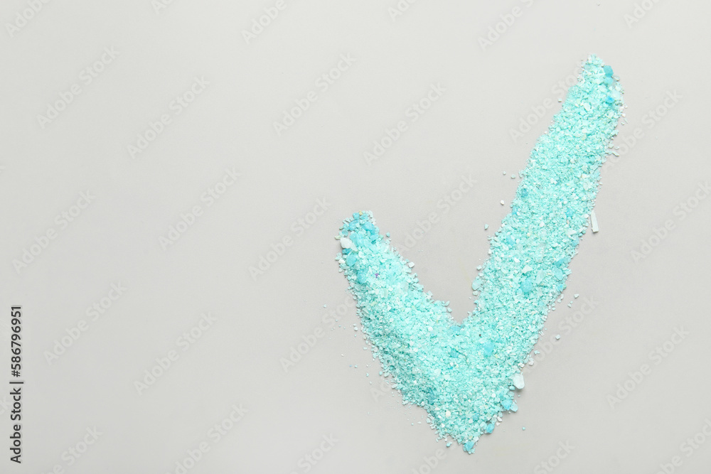 Check mark made of sea salt on grey background