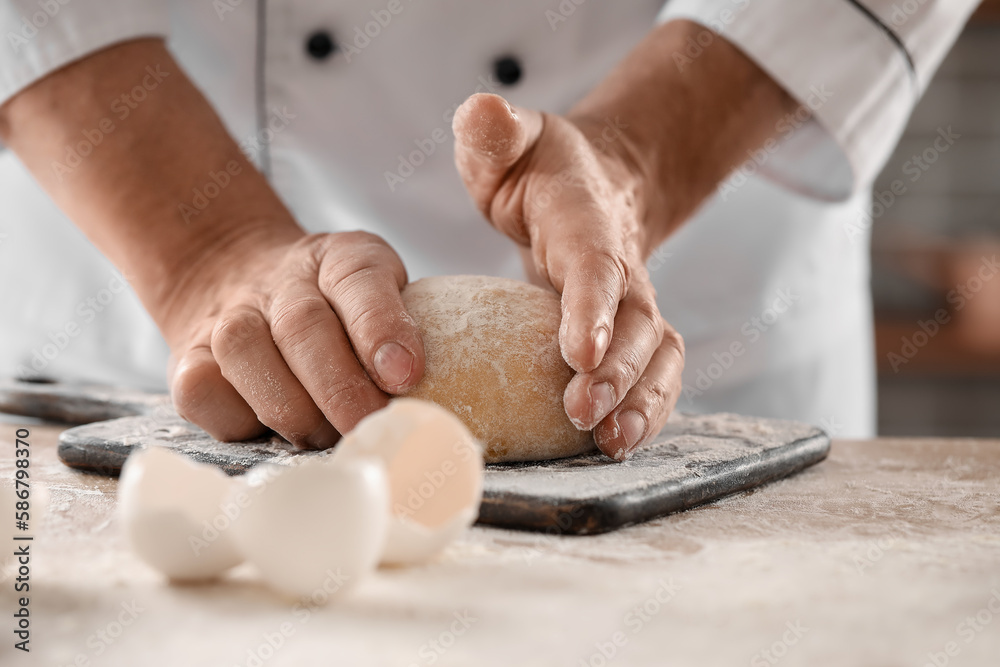 Male chef preparing dough for pasta at table in kitchen, closeup