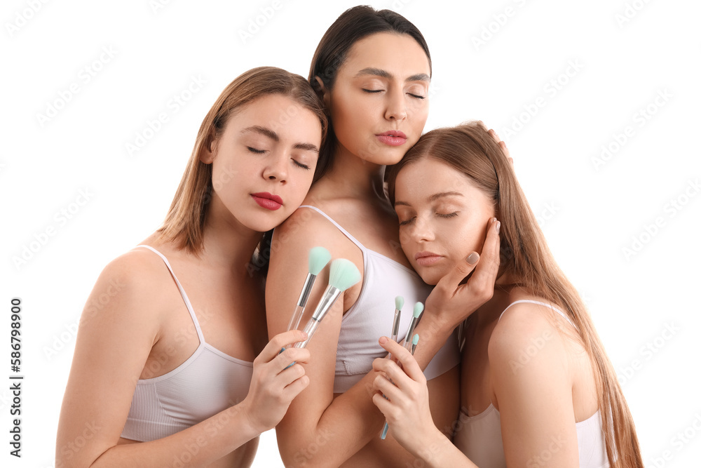 Young women with makeup brushes on white background