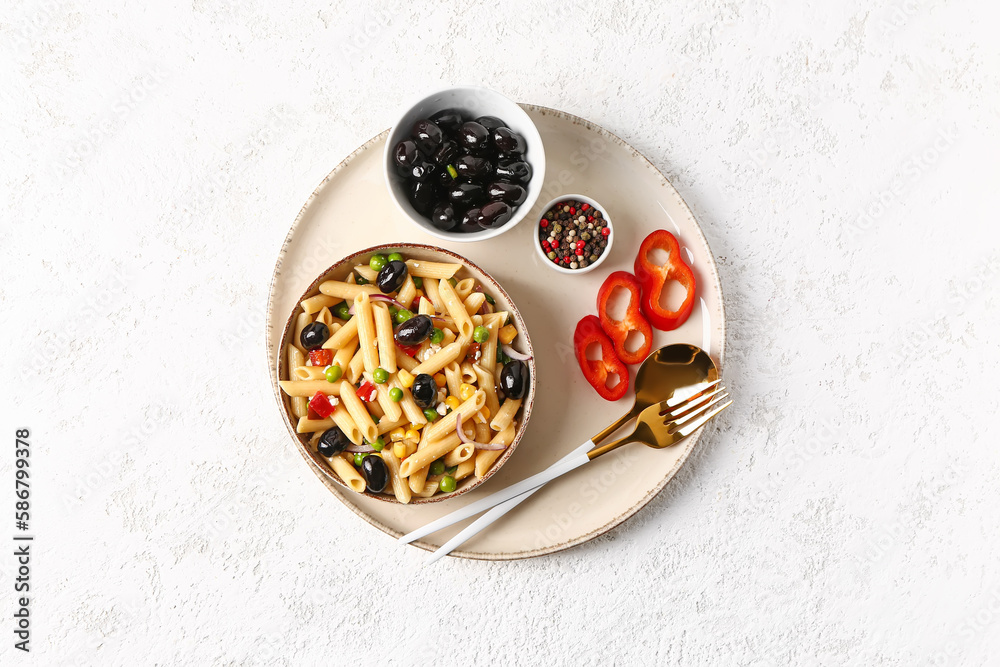 Bowls with tasty pasta salad and black olives on light background