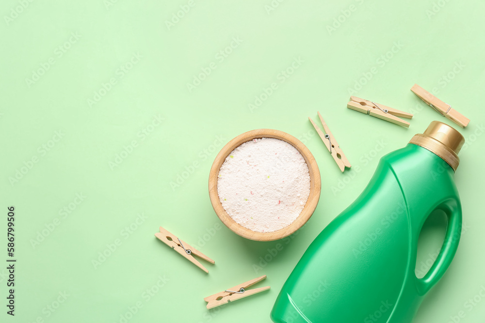 Laundry detergents and clothespins on green background