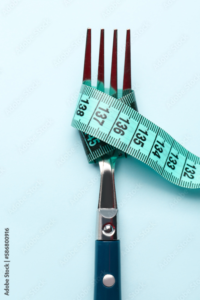 Measuring tape and fork on blue background