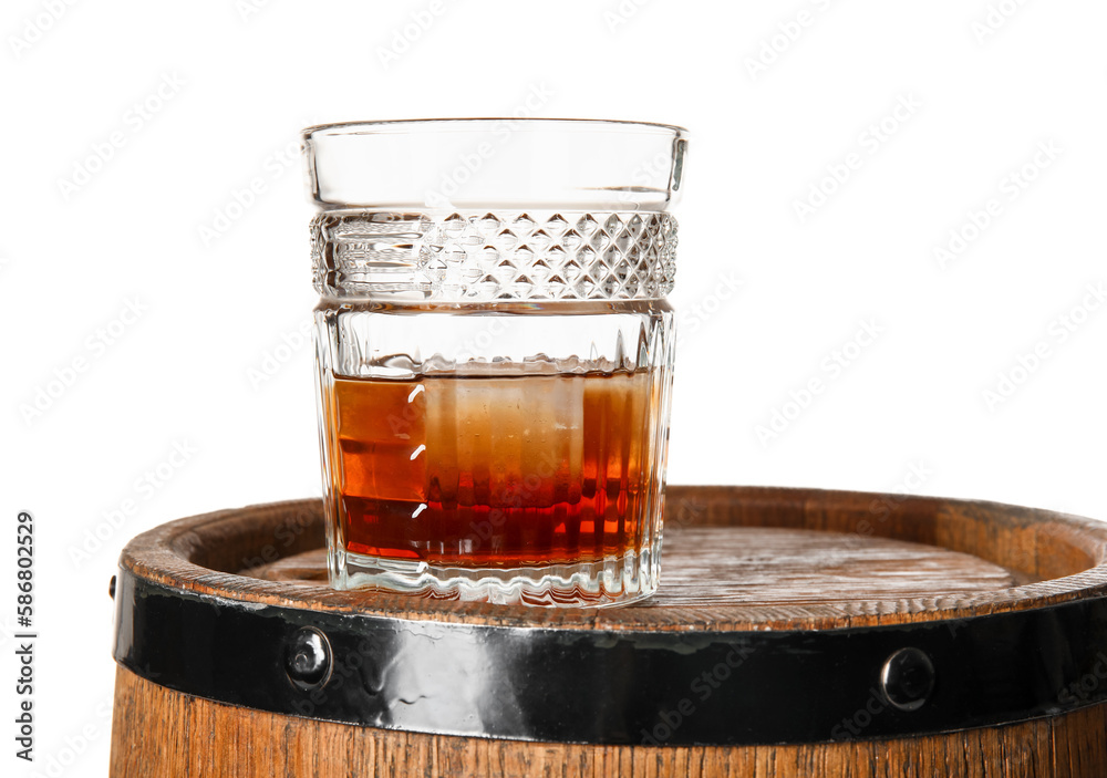 Glass of cold rum on wooden barrel against white background