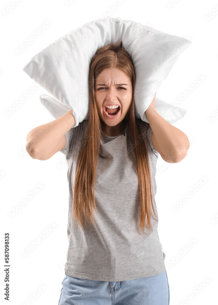 Irritated young woman with pillow suffering from loud noise on white background