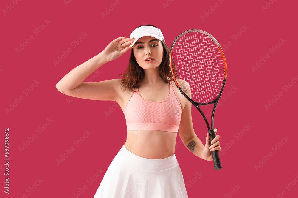 Young woman with tennis racket on pink background