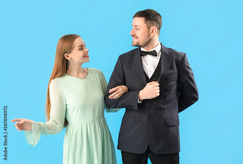 Elegant young couple holding hand in hand on blue background