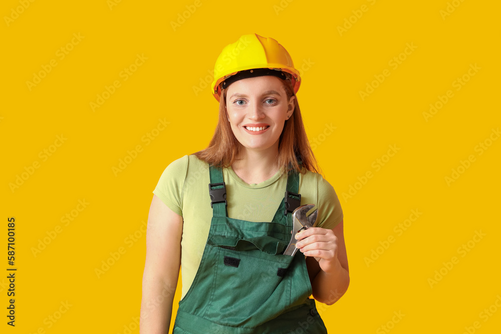 Female builder in hardhat on yellow background