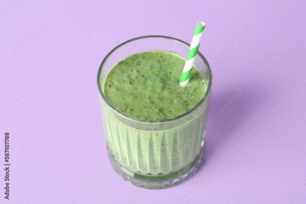 Glass of tasty green smoothie with straw on violet background