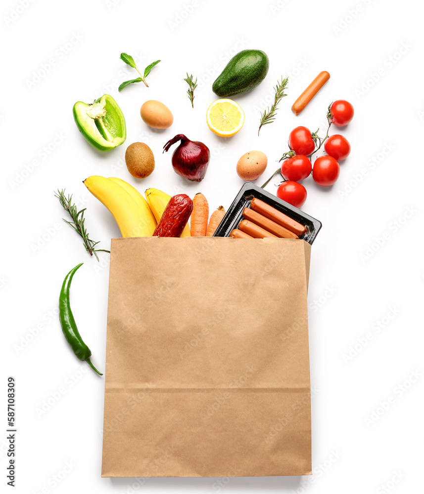 Paper bag with vegetables, fruits and sausages on white background