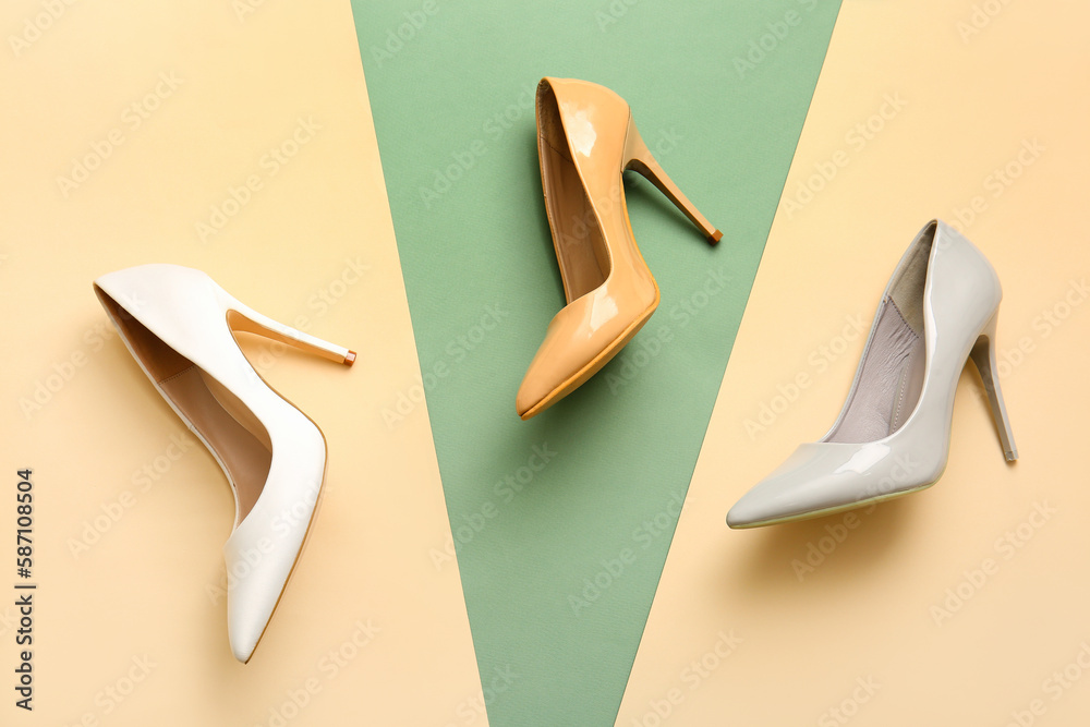 Stylish high heeled shoes on color background, top view