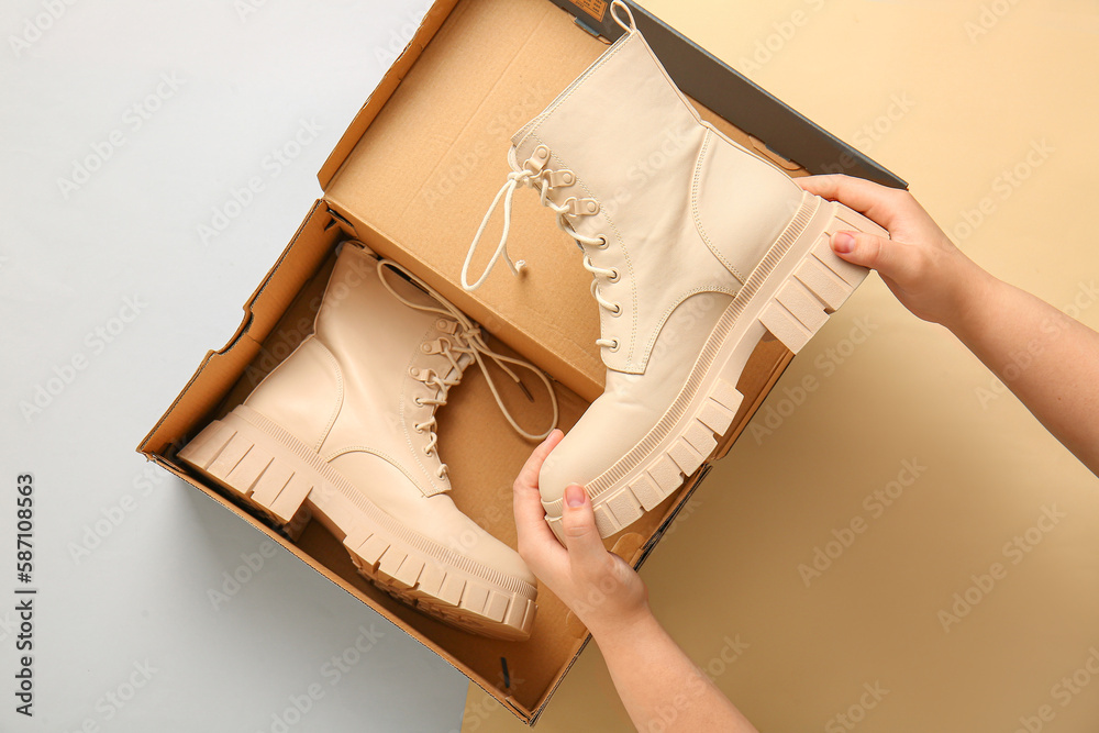 Woman taking stylish shoes out of cardboard box on color background