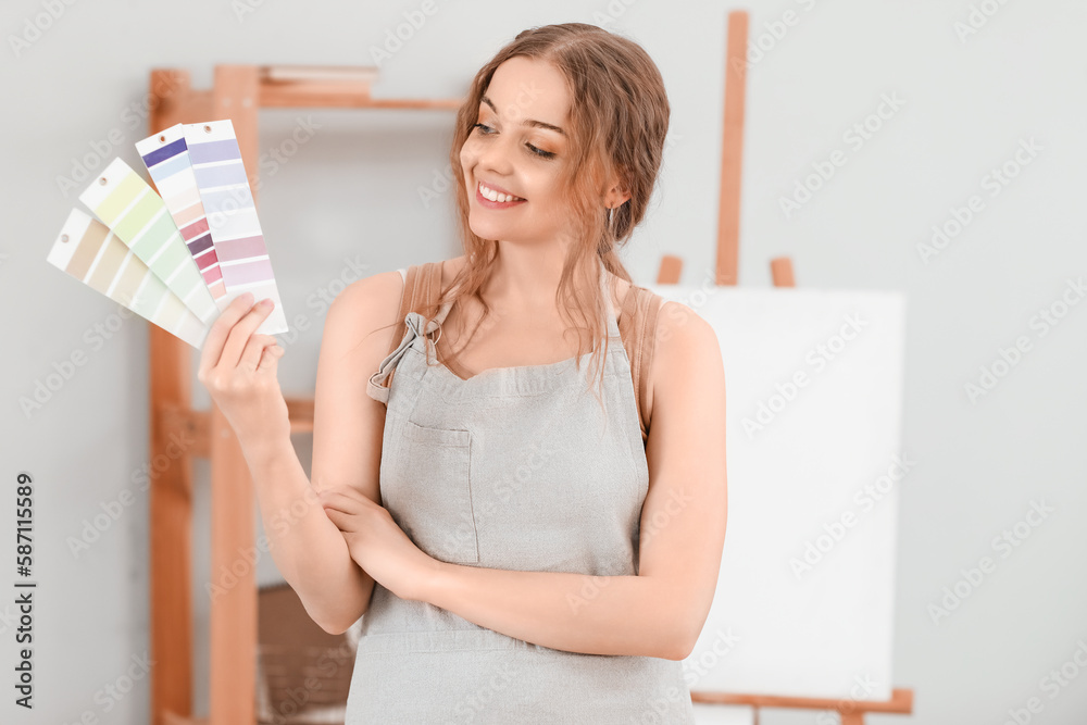 Female artist with paint color palettes in workshop