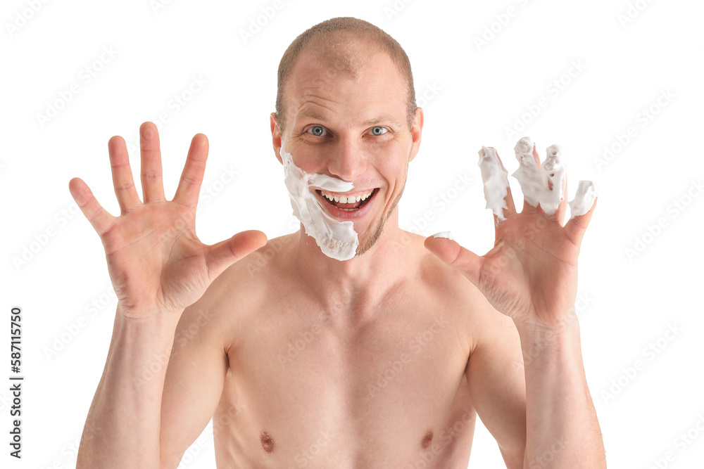 Funny young man with shaving foam on face against white background