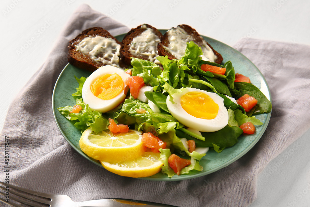 Plate of delicious salad with boiled eggs and salmon on white wooden background