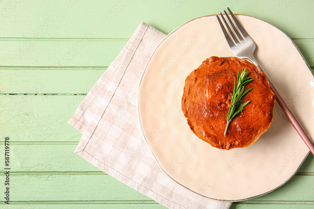 Board with delicious meat pie and fork on green wooden table