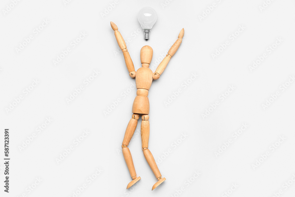 Wooden mannequin with light bulb on light background. Insight concept