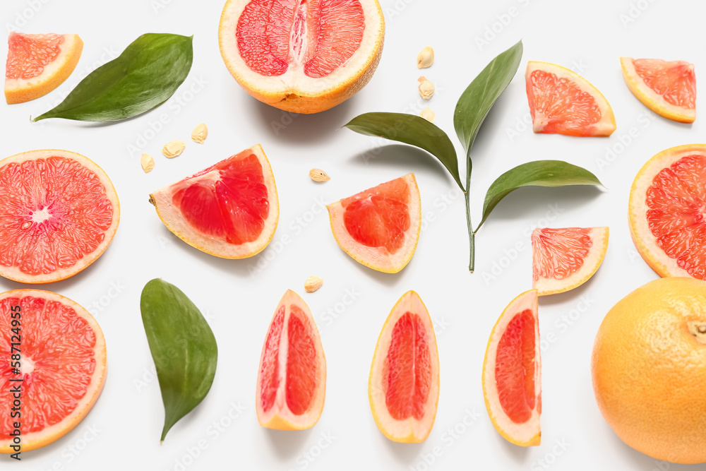 Composition with pieces of ripe grapefruit, seeds and plant leaves on white background