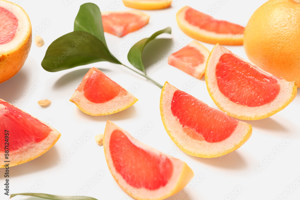 Composition with pieces of ripe grapefruit, seeds and plant leaves on white background, closeup