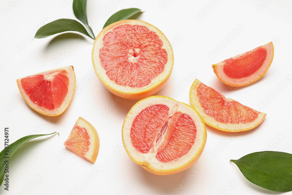 Composition with pieces of juicy grapefruit and plant leaves on white background