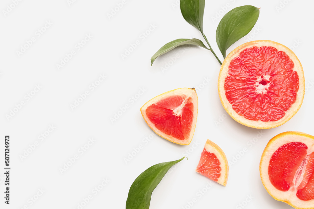 Composition with pieces of juicy grapefruit and plant leaves on white background