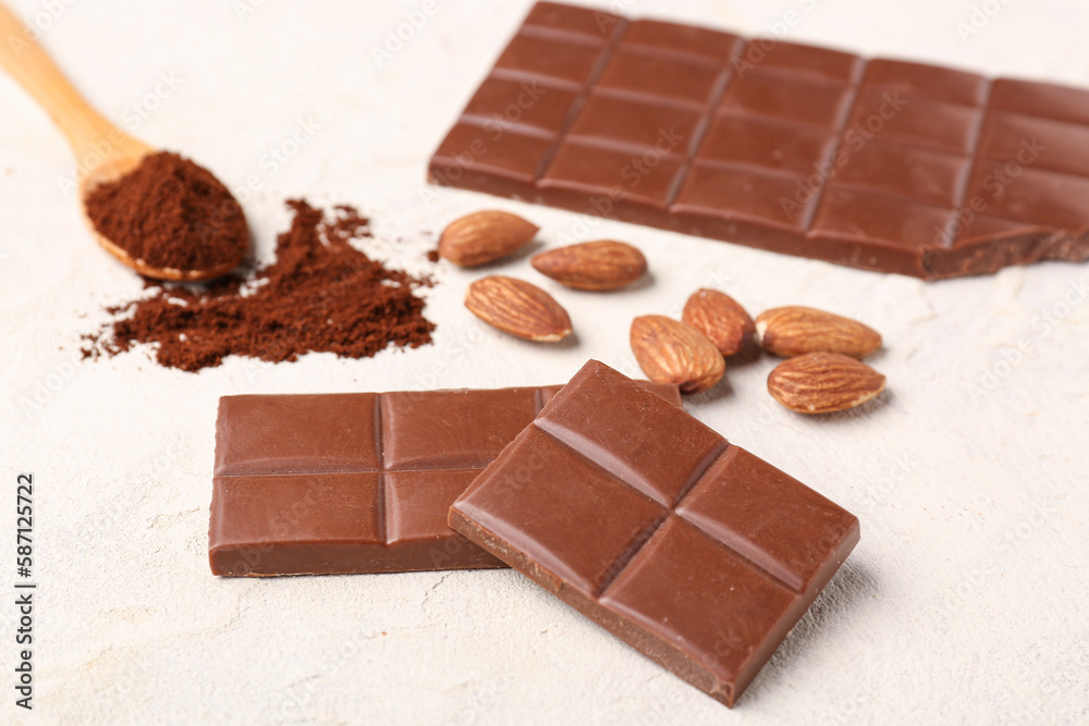 Tasty chocolate, almond nuts and coffee powder on light background, closeup