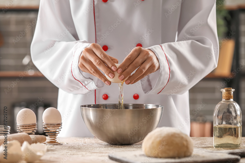 Female chef making dough for pasta at table in kitchen, closeup