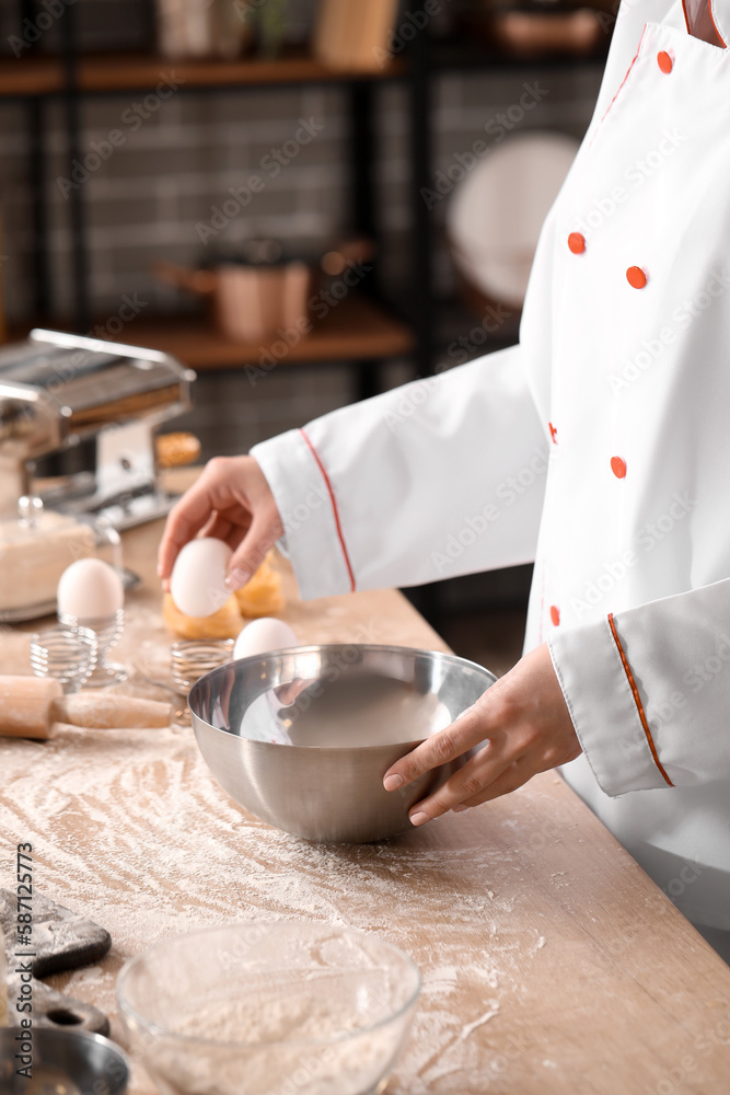 Female chef making dough for pasta at table in kitchen, closeup