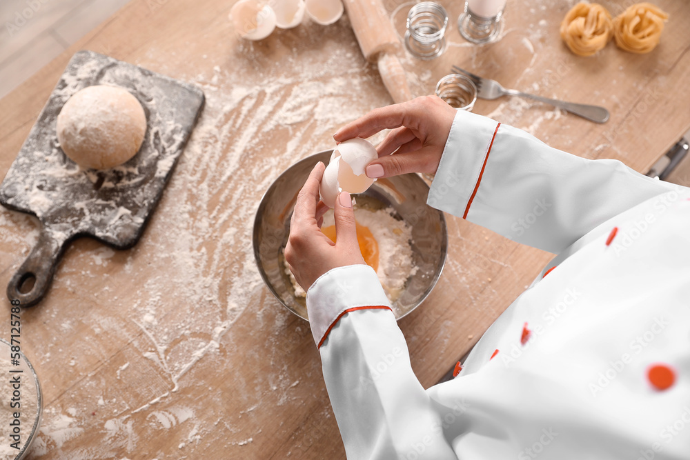 Female chef making dough for pasta at table in kitchen, closeup