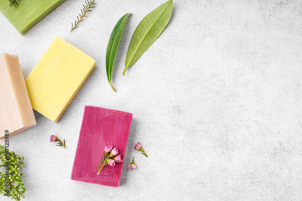 Composition with natural soap bars, plant leaves and flowers on light background