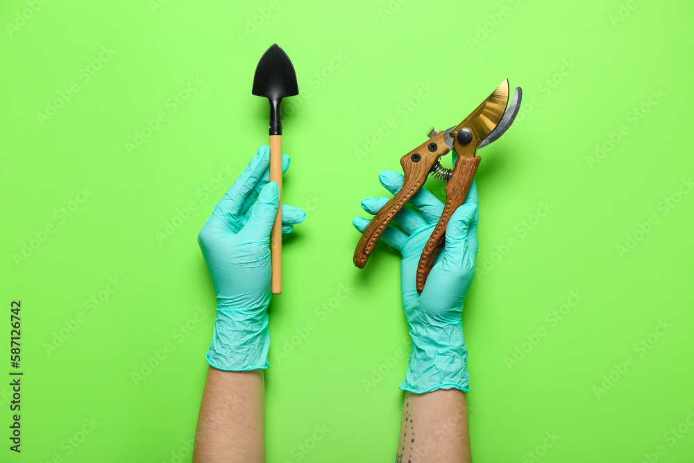 Gardener in rubber gloves with tools on green background