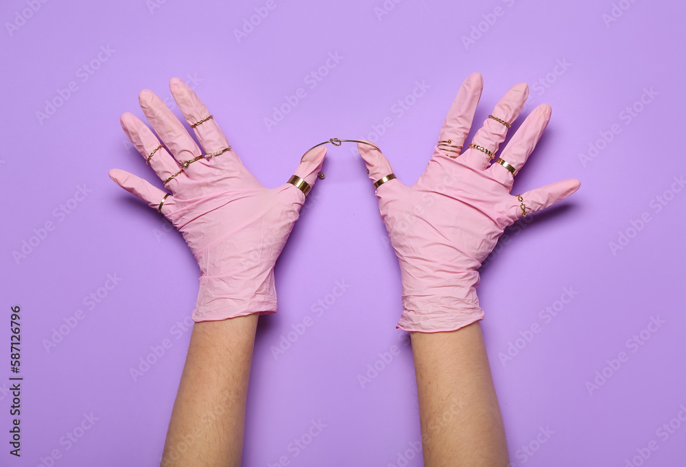 Woman in pink gloves with rings on lilac background